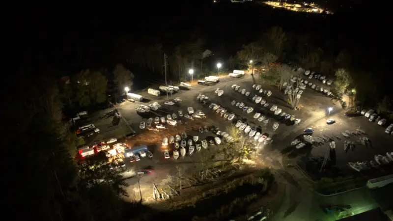 A parking lot filled with various boats, showcasing different sizes and colors, under Night time lighting Storage Lot Layout<br />
